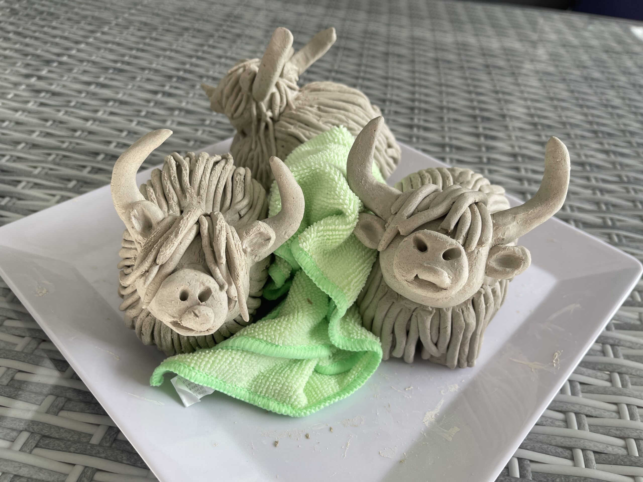 Unfinished clay Highland cows before their first firing