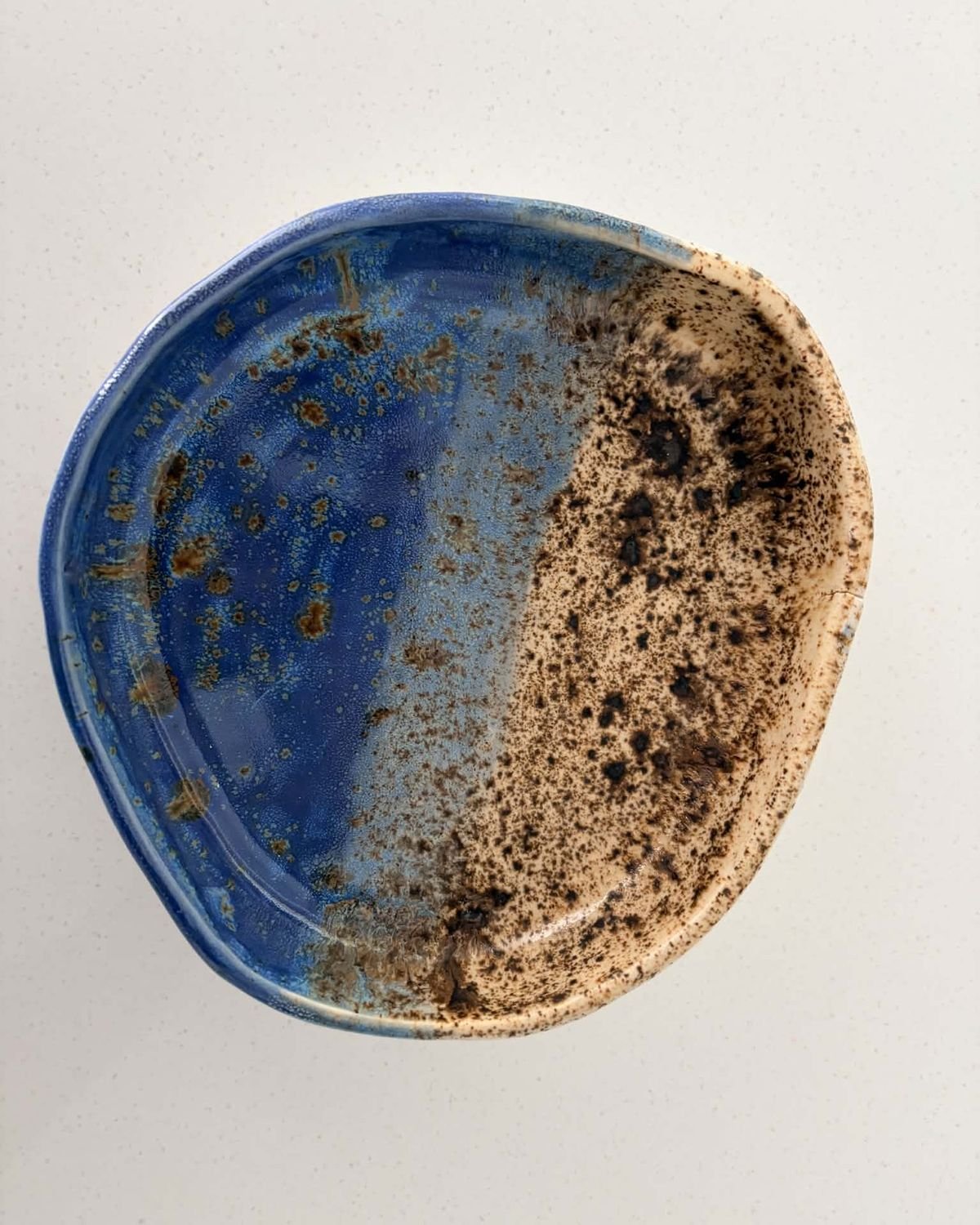 Small organic dish, half deep blue glaze and half speckled oatmeal