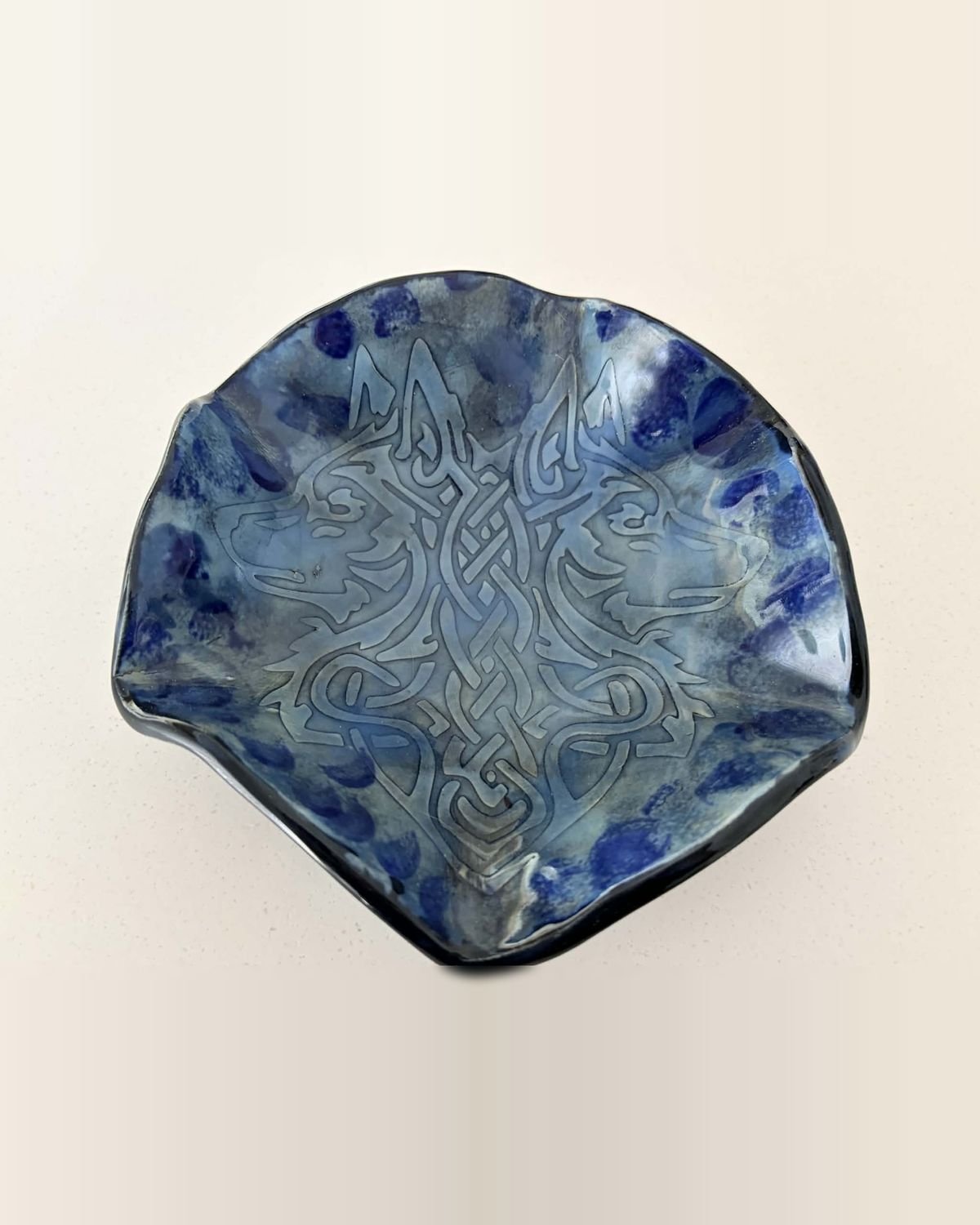 Wavy-edged dish carved with a Celtic knot pattern under cobalt and pale blue glaze