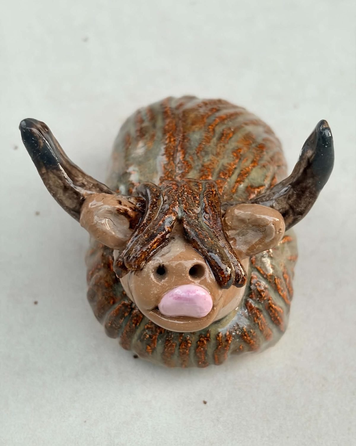 Dougal, a handmade ceramic Highland cow with a brown coat, dark horns and a fringe right over the eyes