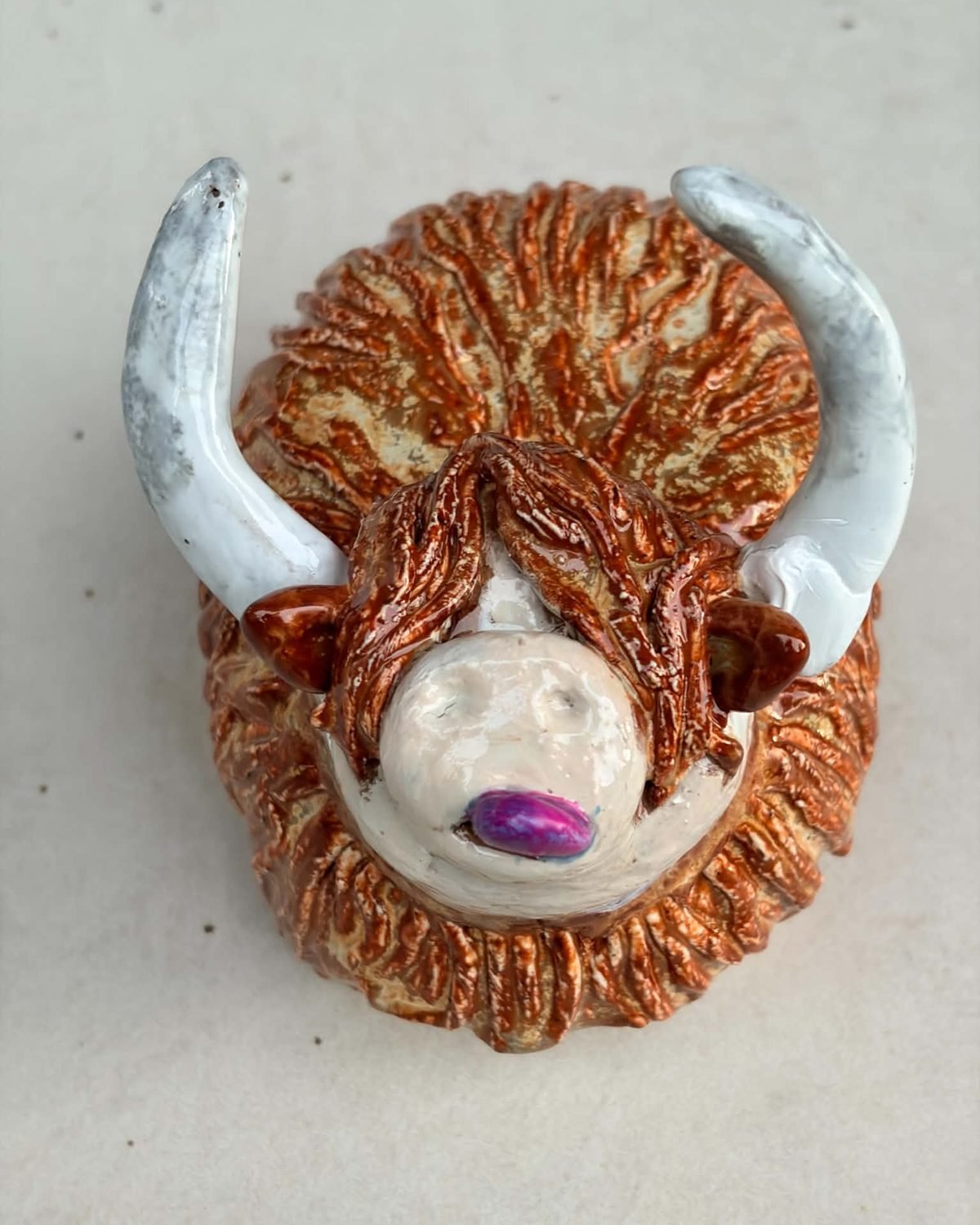 Morag, a handmade ceramic Highland cow with a ginger shaggy coat, white horns and a purple nose