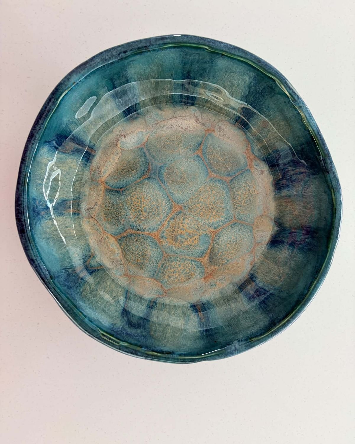 Round bowl with a dimpled centre in teal and sand-coloured glazes