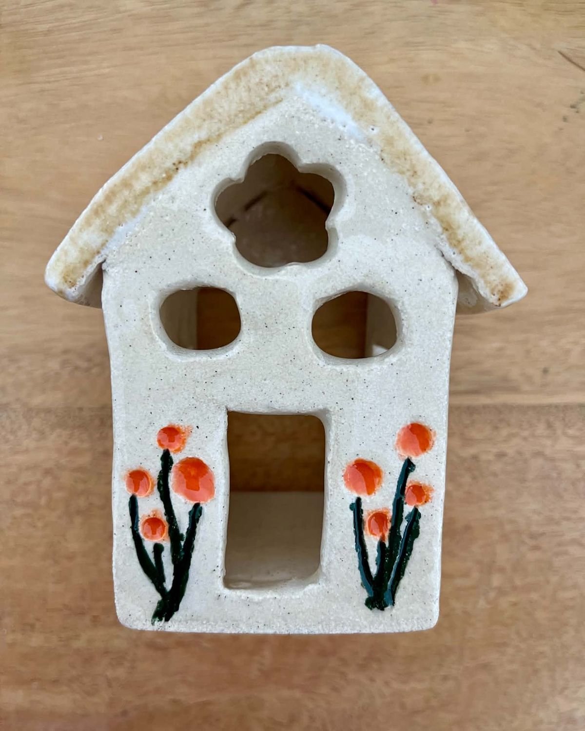 Little white clay house with cut-out windows and painted orange flowers