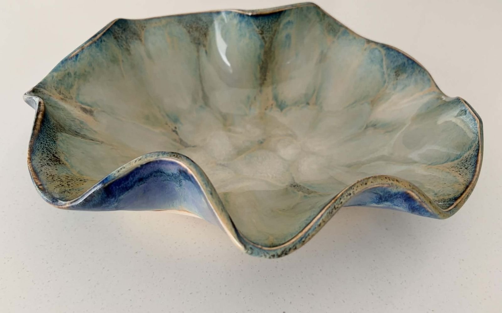 Bowl with a dramatic wavy rim, pale green inside and blue underneath